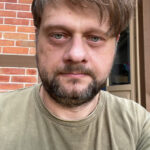 mężczyzna w średnim wieku w krótkich włosach i krótkim zarostem w tiszercie.