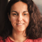 kobieta w kręconych ciemnych do ramion włosach szeroko uśmiechnięta. jest to Dororta Mentecka-Janek